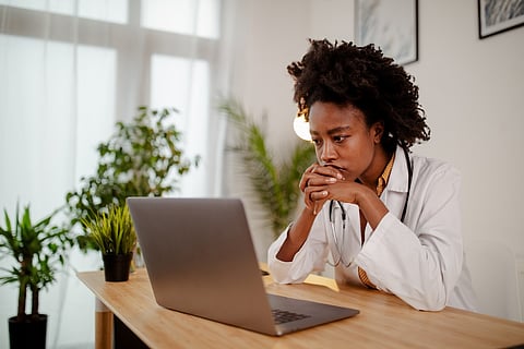 Worried black female doctor working on computer at her desk