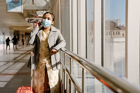 Indian woman wearing face mask talking on mobile phone in airport