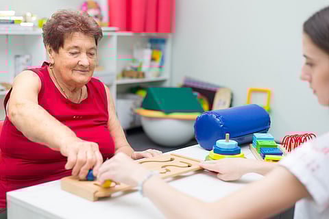 Old woman suffering from stroke exercising on physiotherapy with help of physiotherapist in the hospital