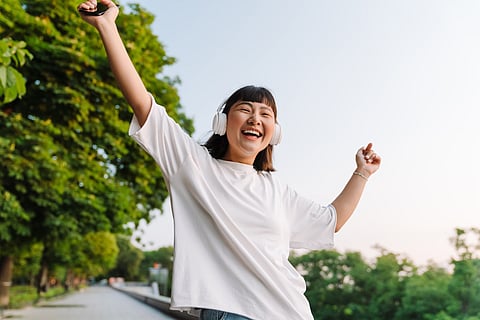 Smiling young asian woman walking in a green park