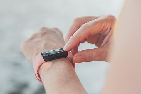 Female hiker using smart bracelet during trekking in nature