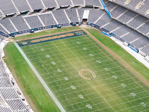 An aerial view of Soldier Field, home to the Chicago Bears, looking towards the Chicago skyline in the fall with snow on the ground.