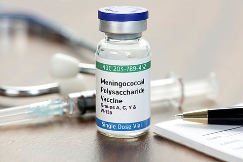 Meningococcal Polysaccharide Vaccine Vial on physician's desk with syringe, stethoscope, and prescription pad