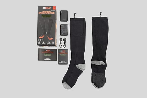 Recalled 32 Degrees Heated Socks with rechargeable battery pack, user manual and packaging against a gray background.