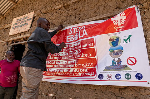 A man hangs an Ebola awareness banner in the Kigonze camp in Bunia, in the eastern Democratic Republic of the Congo