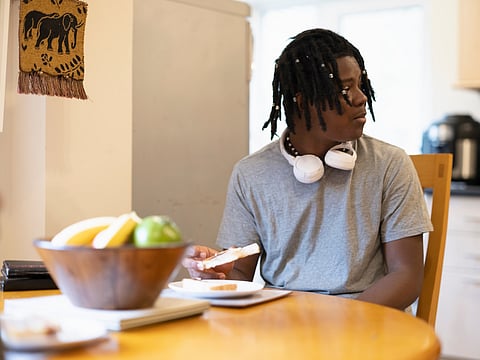 Teenage boy eating toast at table