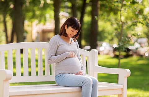 Pregnant woman sitting outside on sunny day