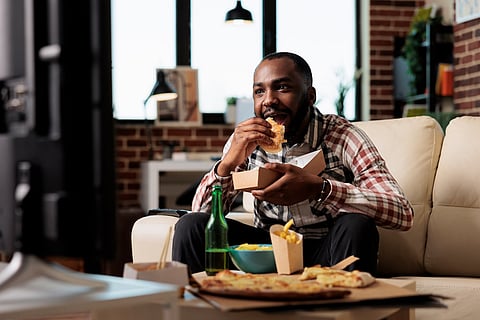 Hombre comiendo hamburguesa y patatas fritas, alimentos ultraprocesados
