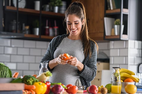 Mujer embarazada comiendo frutas y verduras