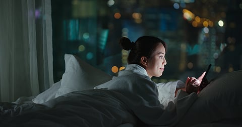 Luz nocturna intensa, mujer hablando por teléfono en la cama