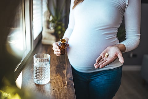 Mujer embarazada tomando medicamentos, paracetamol