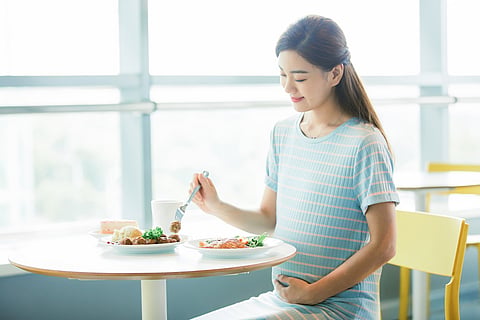 Mujer embarazada siguiendo una dieta mediterránea y comiendo alimentos saludables.