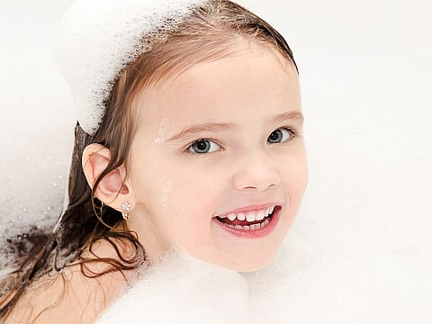 Smiling little girl washing in bath with foam closeup