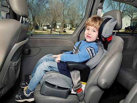 Boy in a booster seat in the back of a van