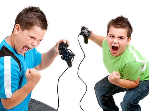 Two boys with victorious face expressions playing with video consoles. Isolated on white.