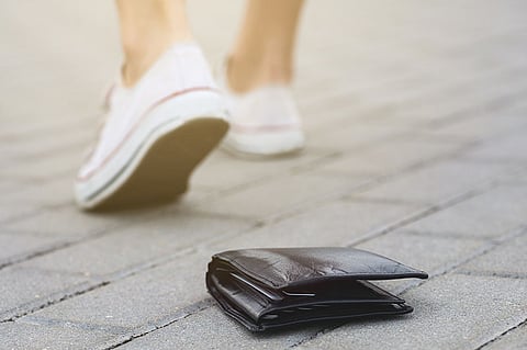 Lost leather wallet on the ground and walking away person