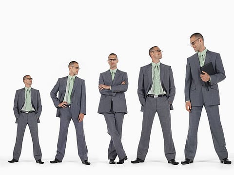 Row of businessmen in ascending order of height against white background