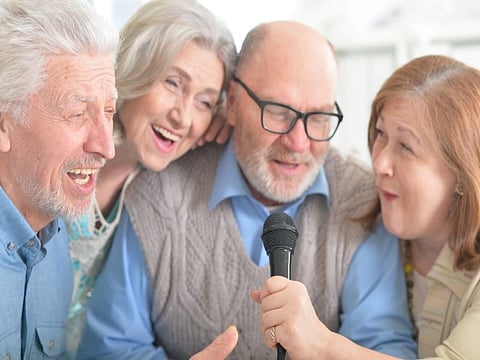 Portrait of two senior couples singing karaoke