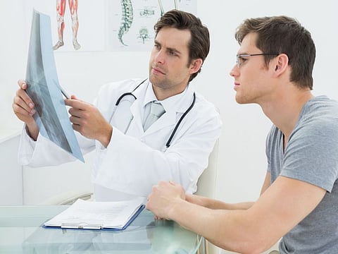Male doctor explaining spine x-ray to patient in the medical office