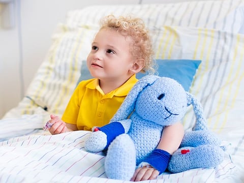 Little boy playing with his toy in bed in hospital room. Child with IV tube and pulse oximeter in modern clinic. Kid recovering from sickness. Post operative care at children station. Kids health care