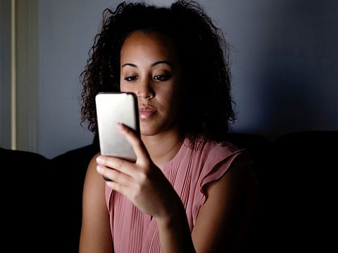 Young girl using her mobile at night on the couch