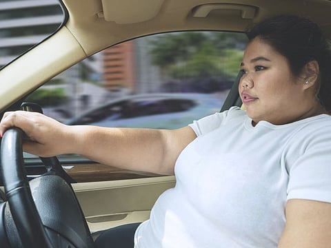 Picture of fat woman driving a car without a seat belt. Shot on the road