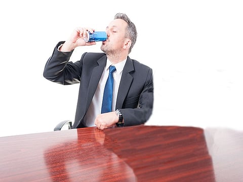 Man wearing suit at office drinking energy drink isolated on white background