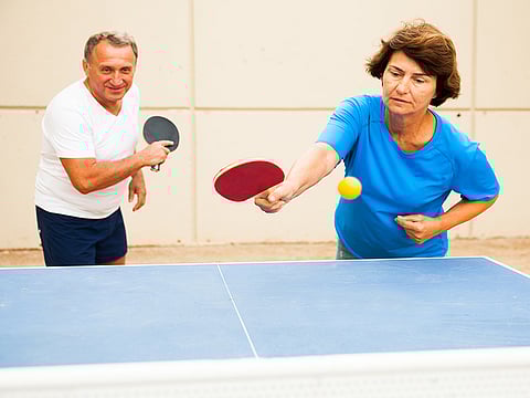 mature couple playing ping pong outdoors at outdoor