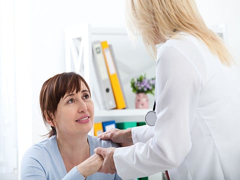Female Patient Being Reassured By Doctor In Hospital Room