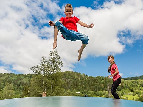 Two scandinavian kids playing and having fun while jumping on large inflatable bouncing pillow.