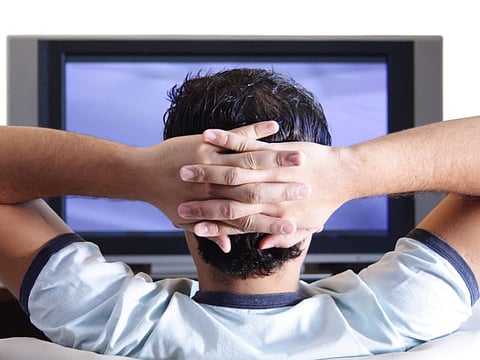 A young adult watching TV.
