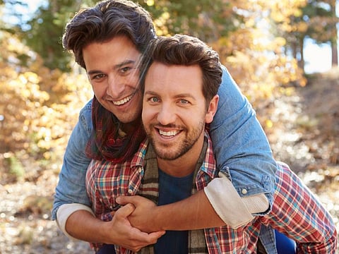 Portrait Of Gay Male Couple Walking Through Fall Woodland