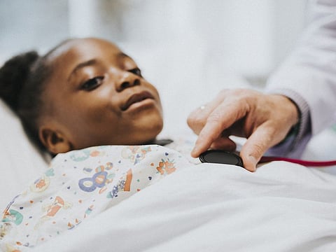 Physician listening to the heart beat of a little girl