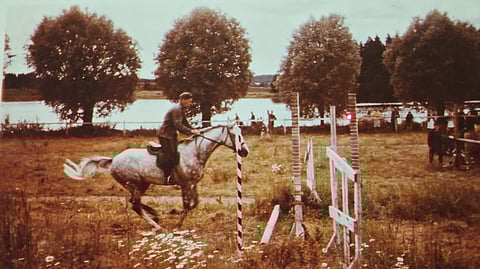 Ville Koski hyppää hevosellaan esteitä Aulangon maisemissa.