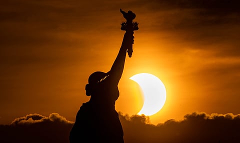The Statue of Liberty with the solar eclipse in the background