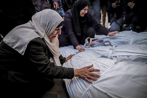 Palestinian women mourn over the bodies of their family after Israeli airstrikes on Gaza. 