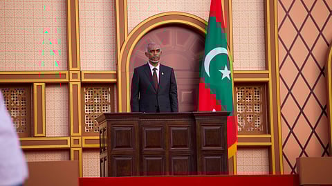Mohamed Muizzu stands behind a wooden podium with the Maldives behind him on the right at his oath-taking ceremony as president of the Maldives in 2023. 