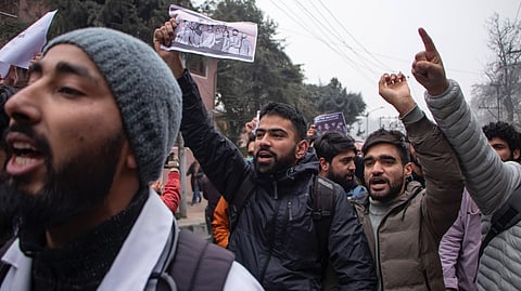 Young men dressed in warm clothed holding up banners and shouting slogans at a student demonstration in December 2024 against a reservation policy.