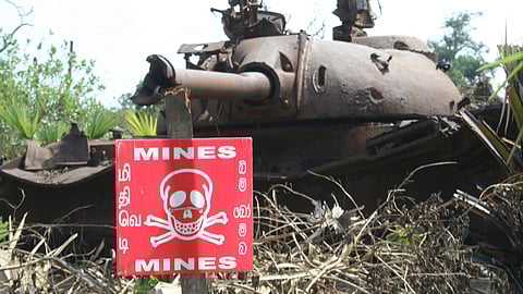 Photo of an army tank with a poster warning of mines in the foreground in Sri Lanka