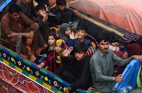 Afghan refugee children wave at the camera from the back of a truck leaving from Pakistan to Afghanistan in April 2025.