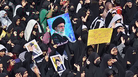 Kashmiri Muslim girls wearing hijab hold a poster of slain Iranian Supreme Leader Ali Khamenei during a demonstration in Budgam district in India-administered Kashmir on 13 March protesting his killing in US airstrikes.