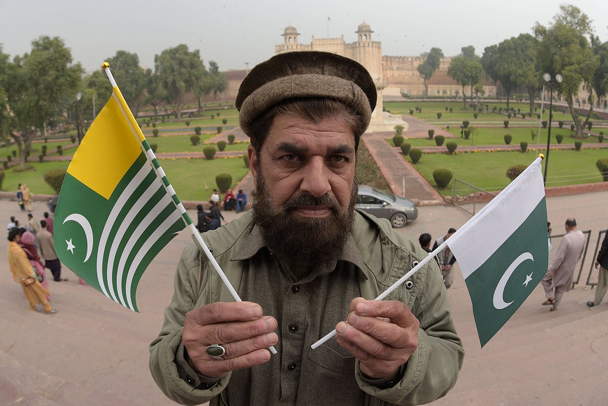 A man holding the flags of Pakistan and Azad Kashmir.
