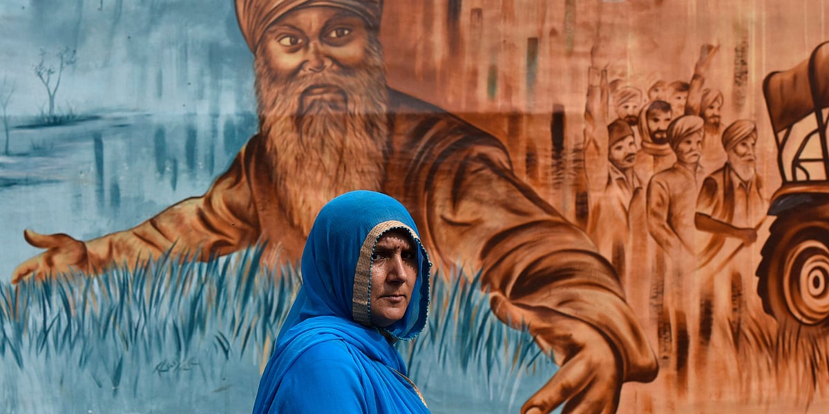 A woman walks past a mural at the Singhu border protest site of the 2021 farmers protests in New Delhi. 