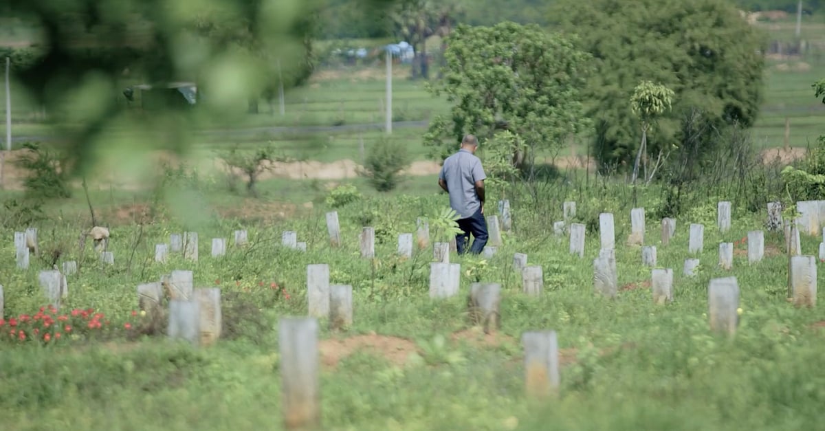 A still from the documentary ‘Oddamavadi’, where a mourner dressed in a grey shirt and black pants walks through an overgrown