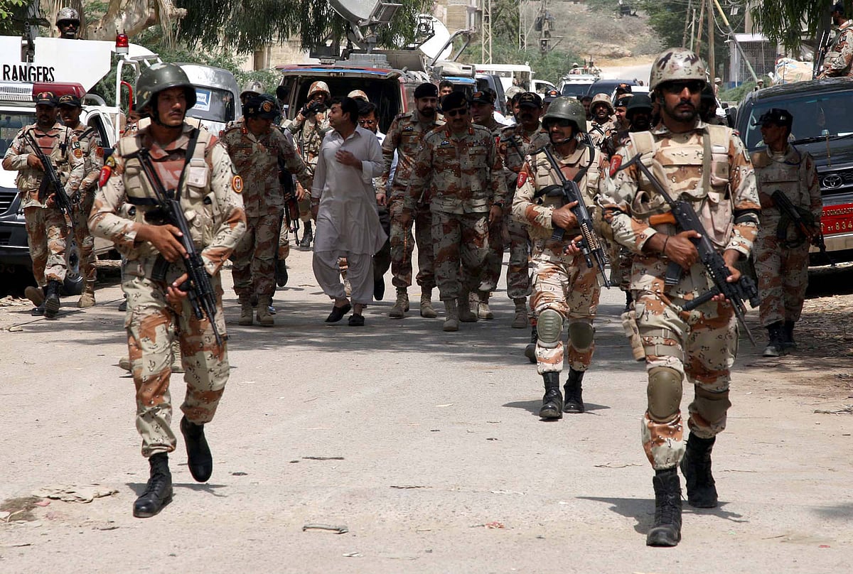 Men belonging to the Pakistan security forces in military camouflage military uniform, boots and helmets and carrying rifles 