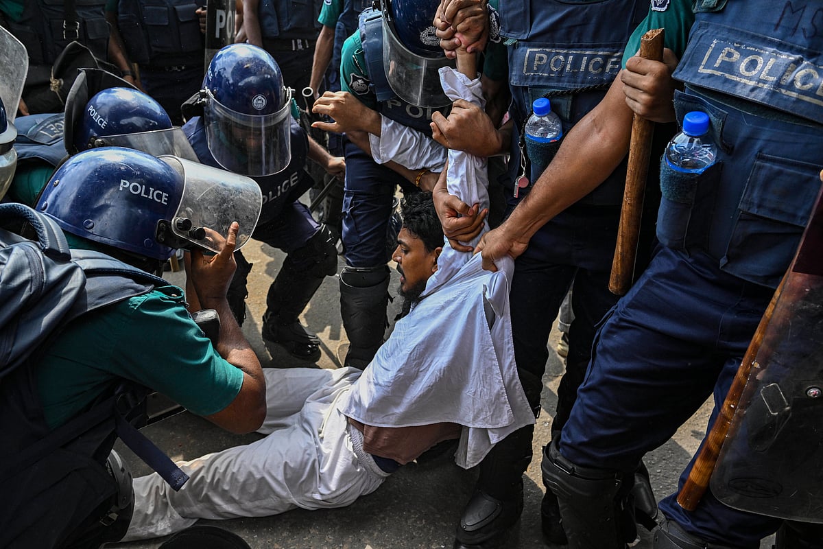 Ten or more Bangladesh police officers drag a protester across the streets of Dhaka by force. 