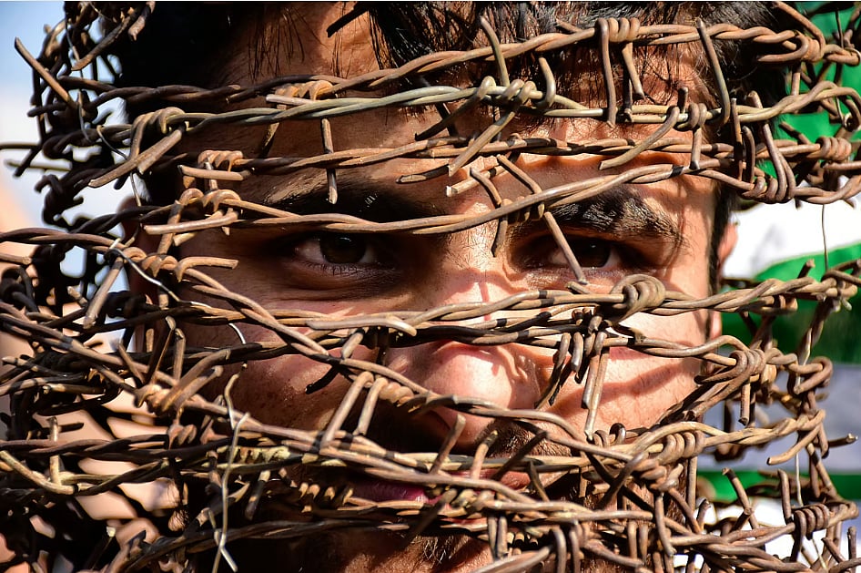 A man covers his head with barbed wire at a protest in Srinagar against the revocation of Article 370 in 2019. 