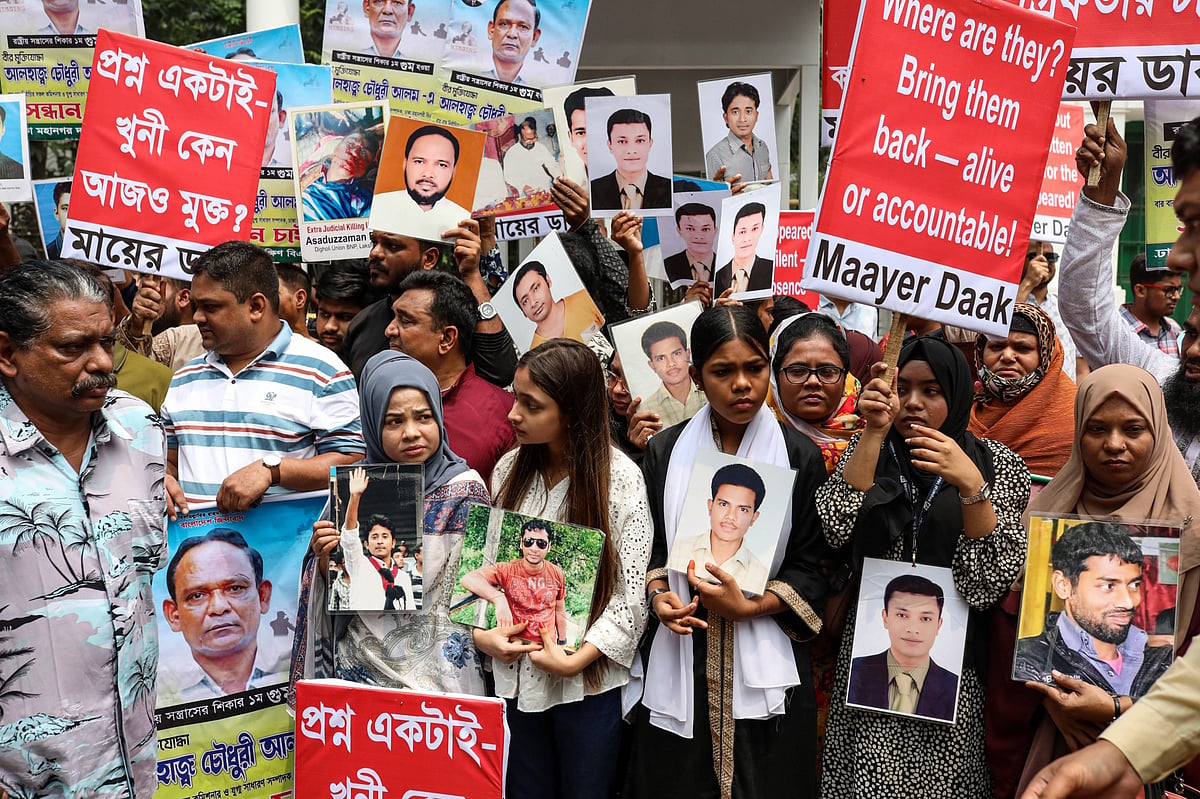A group of activists in Bangladesh participate in a protest holding photographs of missing persons. They are carrying signs w