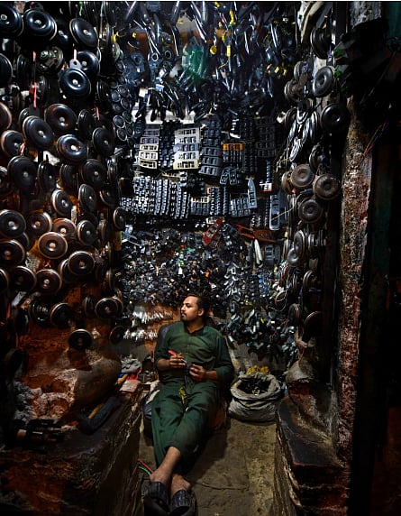 Photo of a man in a machine shop surrounded by machine parts