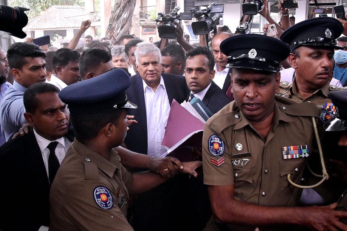 Ranil Wickremesinghe surrounded by police and lawyers coming out of the courtroom after being arrested for misusing state fun